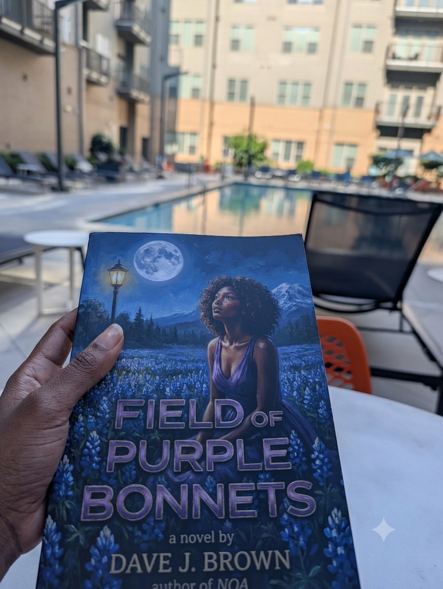 A hand holding the paperback of Field of Purple Bonnets poolside at a Texas apartment complex.